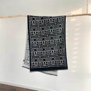 Détail d'une écharpe en cachemire à motif géométrique double face avec de fines franges