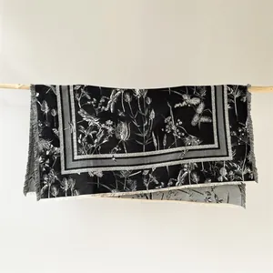 Détail du motif floral et libellule sur écharpe noir et blanc avec bords à franges
