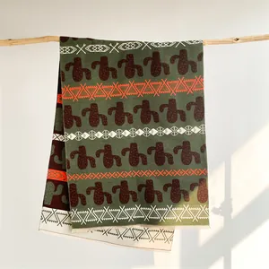Detail of bohemian cashmere-like shawl with cactus print and fringe on wood branch