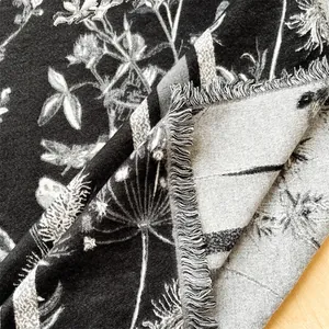 Détails de motif floral noir et blanc et pompons sur un châle en cachemire de haute qualité
