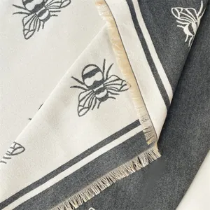 Detail of bee jacquard pattern and fringe edges on gray cashmere feel warm scarf