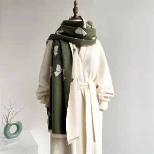 Close-up of olive green cashmere scarf with white bow pattern and fringe tassels