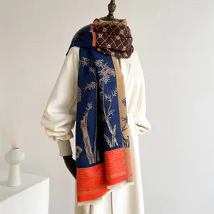 Detail of ethnic cashmere-feel scarf with bamboo print and fringe on a white coat
