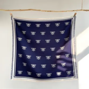Navy blue bee print cashmere-feel scarf shawl with tassels hanging on a wood branch