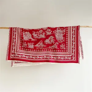Detail of red paisley shawl featuring white nautical patterns and fringe edges