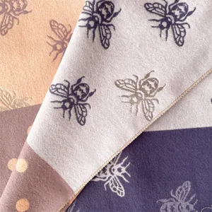 Detailed close-up of thick cashmere scarf with honeybee print and premium stitching