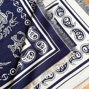 Detailed view of paisley patterns and tassel edges on the thick navy knit shawl