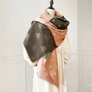 Detailed close-up of cashmere-like scarf with bee patterns, color blocks and fringe trim