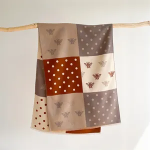 Detail of bee embroidery and polka dots on cashmere-feel color-block winter shawl