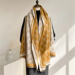Detail of mustard yellow tassel scarf featuring clover geometric patterns and fringe edges