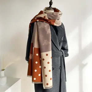 Detail of bee jacquard pattern on a warm orange and beige cashmere-feel scarf