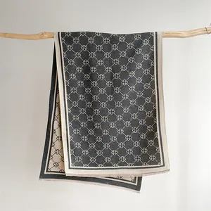 Detail of grey and beige floral pattern shawl with fringe edges on wooden branch
