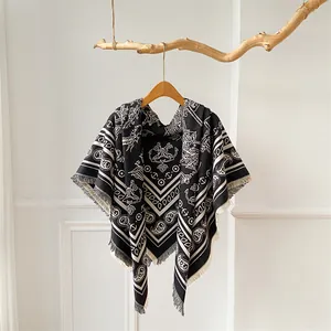 Detail of paisley and coat of arms patterns on a black and white fringed shawl scarf