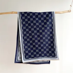 Detailed view of dark blue scarf with geometric floral pattern and soft fringe edges
