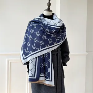Detail of navy and beige cashmere-feel scarf showing double-sided clover pattern and fringe