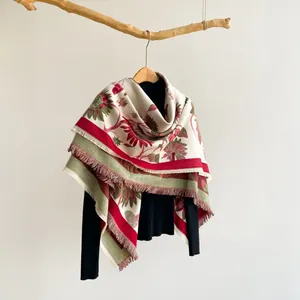 Close-up of vintage floral knit shawl with red and green prints and soft tassel edges
