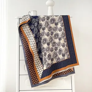 Detail eines Vintage-Schals mit Blumen, Punkten und Fransen auf weißem Schrank