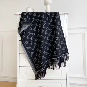 Macro view of thick knitted scarf featuring grey floral motifs and elegant long tassels