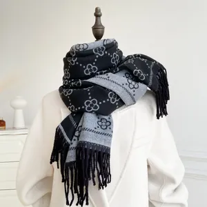 Detail of black and grey cashmere-like scarf with vintage floral pattern and long tassels