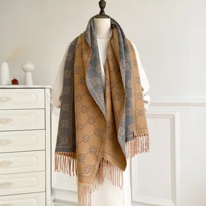Close-up of geometric floral pattern and long tassels on a camel cashmere-feel shawl