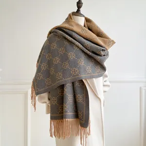Macro detail of deep grey and camel cashmere-feel scarf with floral pattern and tassels