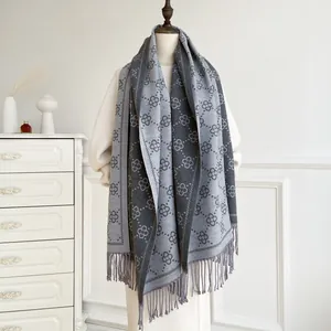 Detail view of soft grey cashmere-like scarf with four-leaf clover pattern and fringe