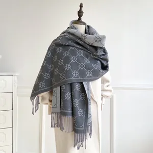 Detail of four-leaf clover jacquard pattern and twisted tassels on grey scarf shawl