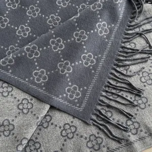 Detailed close-up of double-sided cashmere scarf with clover pattern and fringe tassels