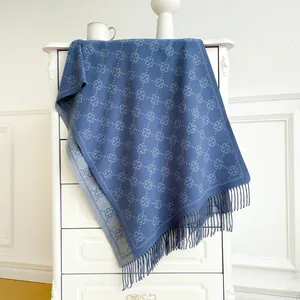 Close-up of navy knit shawl with grey clover jacquard pattern and soft fringe details
