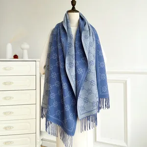Close-up of double-sided blue and grey scarf with clover patterns and long tassels