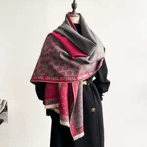 Detail of a thick double-sided cashmere scarf with camellia patterns and tassel trim