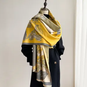 Detail of yellow and grey floral pashmina scarf with fringe on a black coat