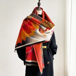 Dettaglio della sciarpa invernale effetto cashmere con stampa floreale arancione e frange
