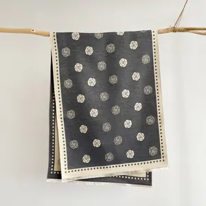 Close-up of vintage camellia jacquard pattern on dark grey scarf with tassel edges