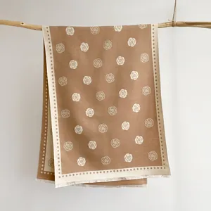 Close-up of caramel jacquard camellia shawl with fringe edges on a wooden branch