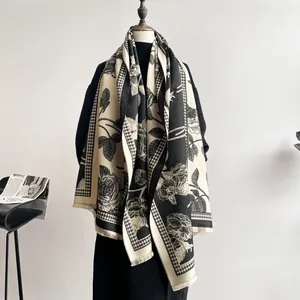 Detail of elegant black and beige winter scarf with large rose patterns and tassels