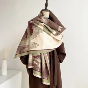 Detail of floral jacquard shawl with tassel fringe draped over a long winter wool coat