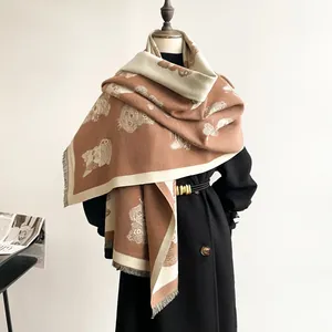 Detail of soft cashmere-like scarf with cute cartoon dog pattern and fringe edges