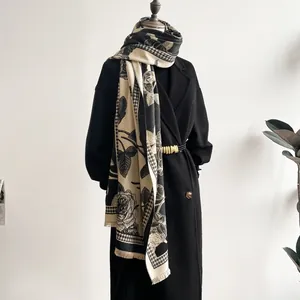Detail of elegant floral and houndstooth thick shawl scarf with fringe on a black coat