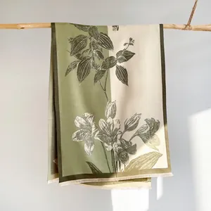 Close-up of floral print pashmina shawl with fine fringe details on olive green fabric