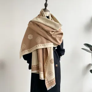 Detail of camellia jacquard pattern and fringe edge on a soft beige cashmere scarf