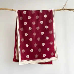 Detailed texture of burgundy camellia jacquard scarf with delicate fringe edges and floral patterns