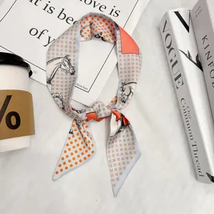 Elegant skinny silk scarf with orange horse pattern and dots, styled on lifestyle books
