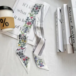 Detailed view of floral twilly silk scarf with 'France Paris' script and coffee props