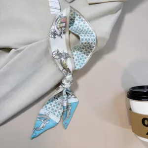 Detail eines hellblauen Twilly-Schals mit Kutschenmuster am beigefarbenen Mantelkragen
