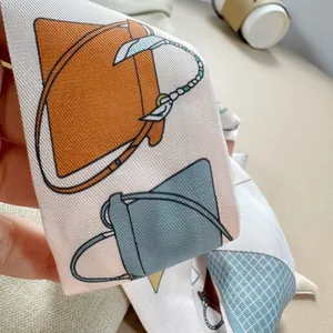 Detail of double-sided twill silk scarf featuring orange and blue handbag print
