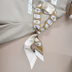 Elegante smalle zijden sjaal met geometrische print op een beige blazer gestyled
