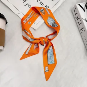 Dettaglio foulard in seta arancione con stampa cancelleria su tessuto e rivista Vogue