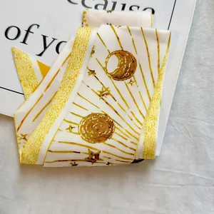 Detail of a yellow satin twilly scarf with star and moon patterns for bags or hair