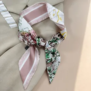 Elegante foulard stretto in seta con stampa floreale tropicale annodato su tessuto beige